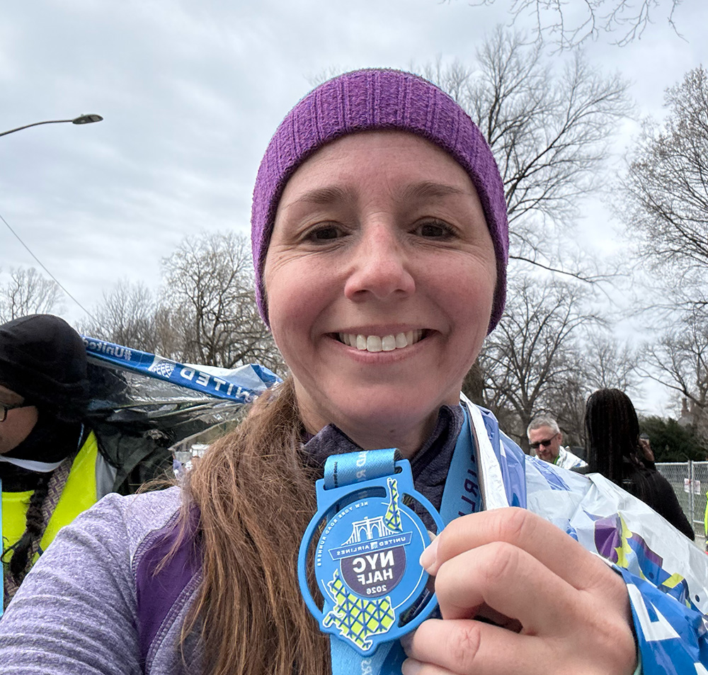 Board member, Erin, shows here medal from the NYC half